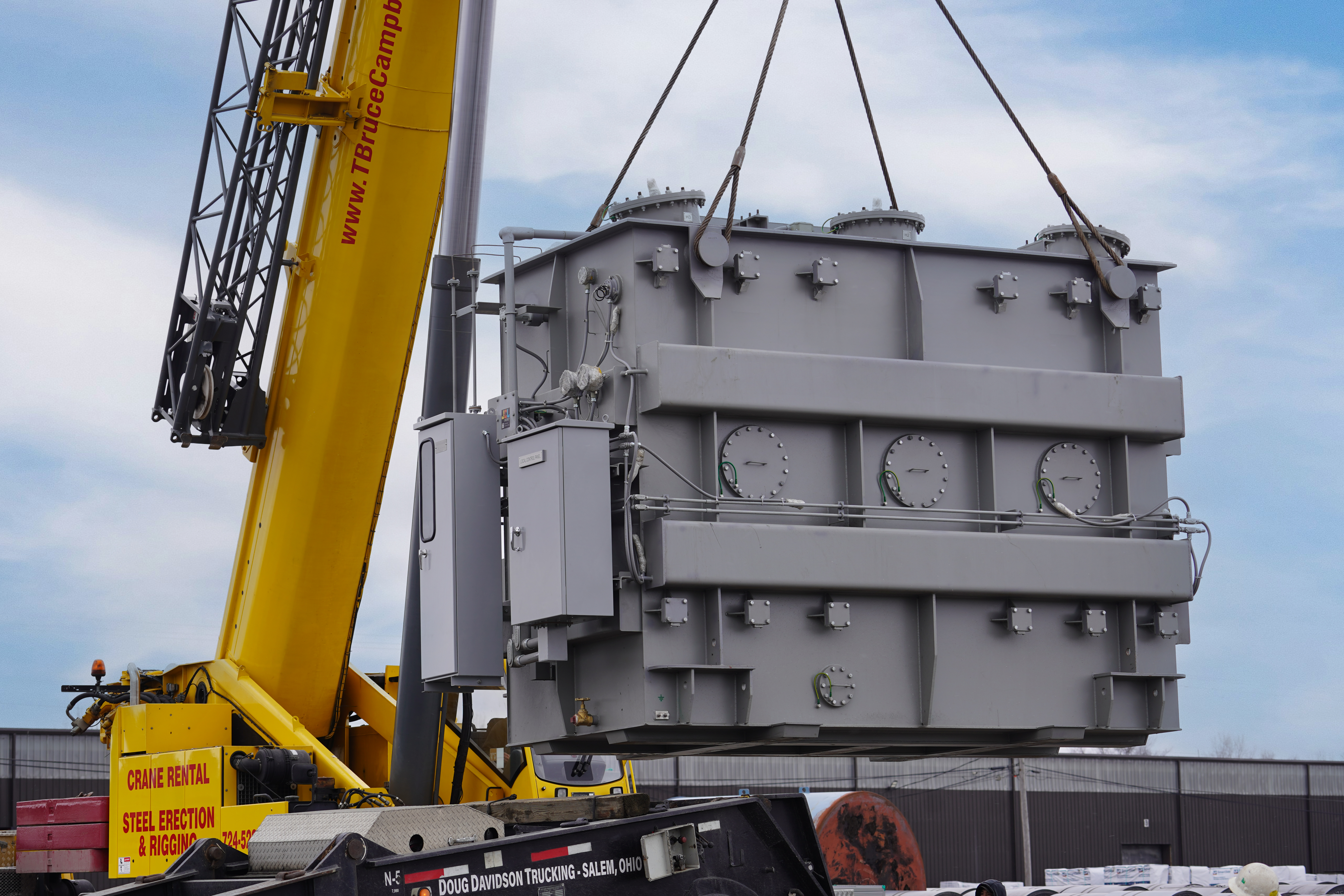 Crane setting a power transformer during site construction