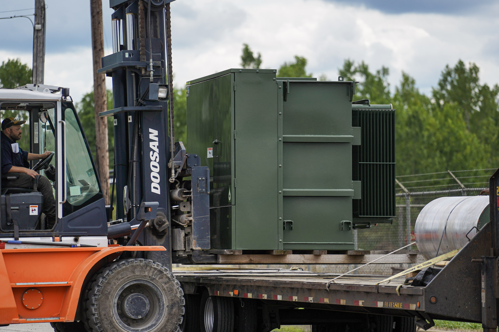 A rental padmount loading onto a flatbed trailer