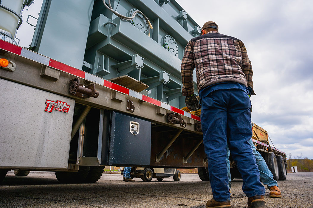 JCL technician strapping down a transformer on a flatbed