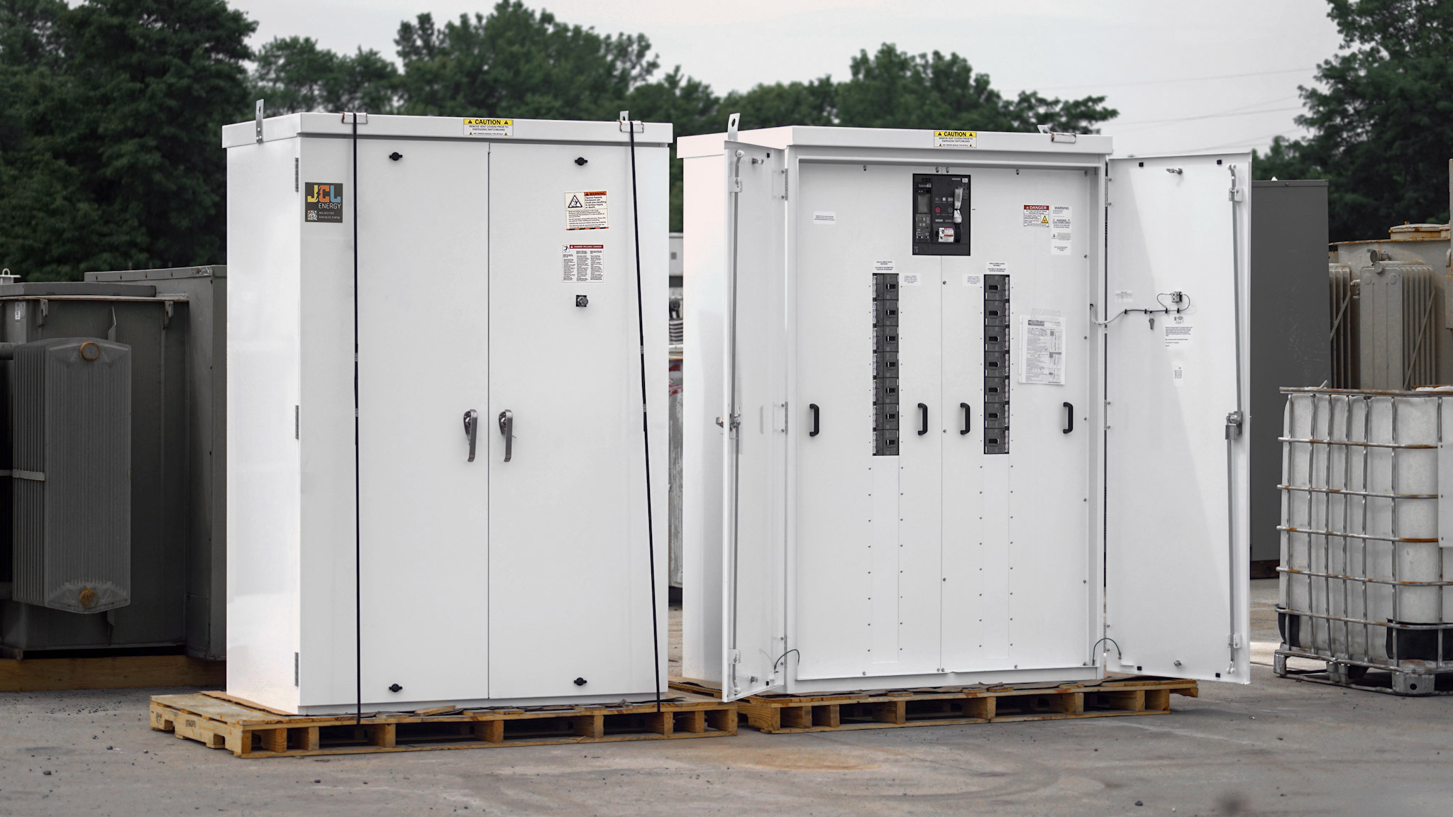 Two JCL 2500 A switchboards staged on pallets in the yard, one with doors open