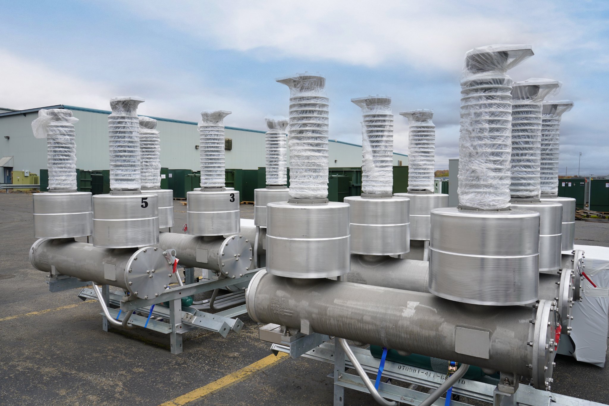 Medium-voltage breakers with wrapped bushings staged in the JCL yard against a cloudy-blue sky
