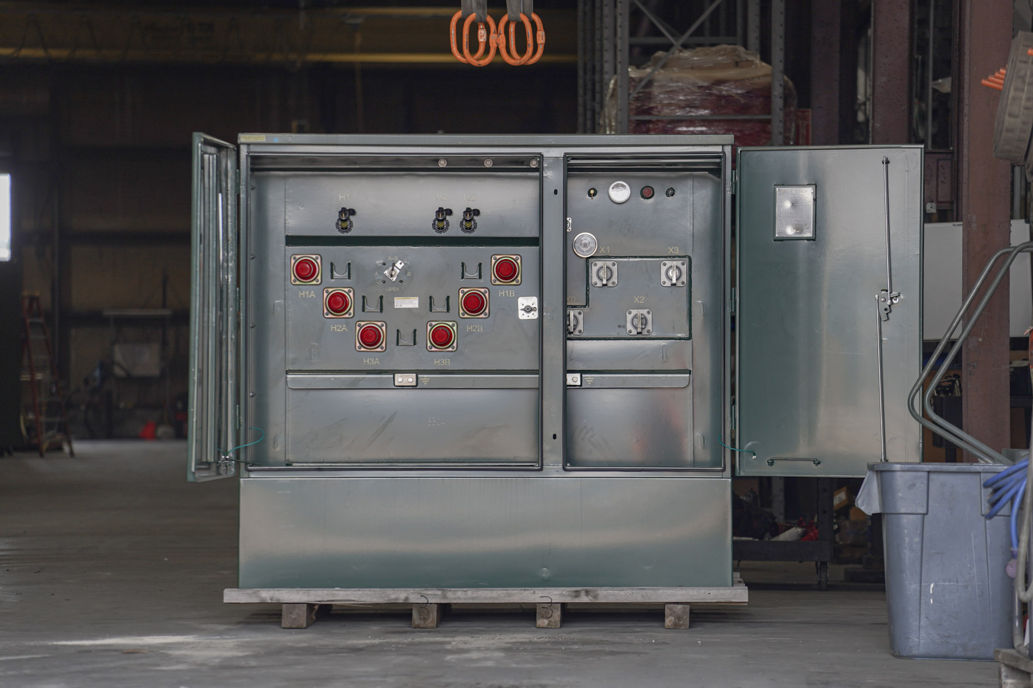 A finished JCL padmount transformer with doors open under the shop crane