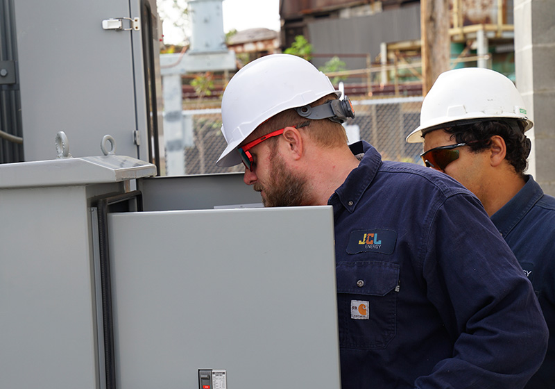 JCL technicians inspecting an open control cabinet